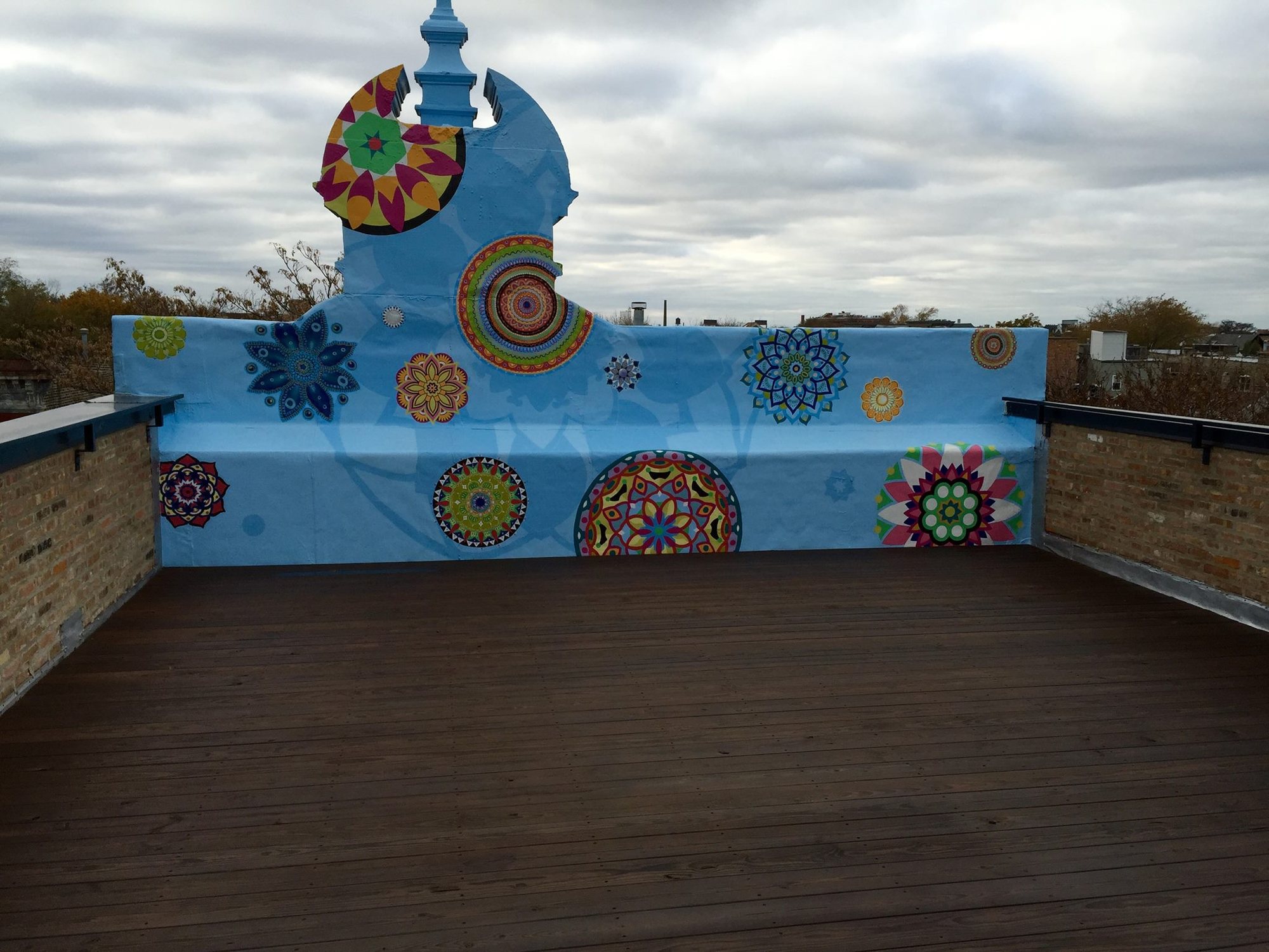 A mandala mural painted on a rooftop deck by Artist Painters
