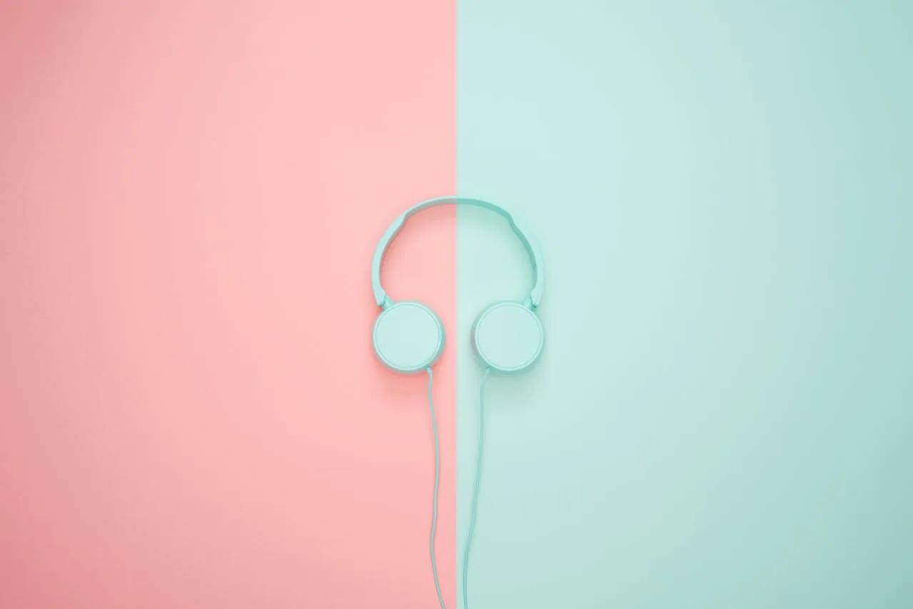 Turquoise headphones on a split pink and turquoise background