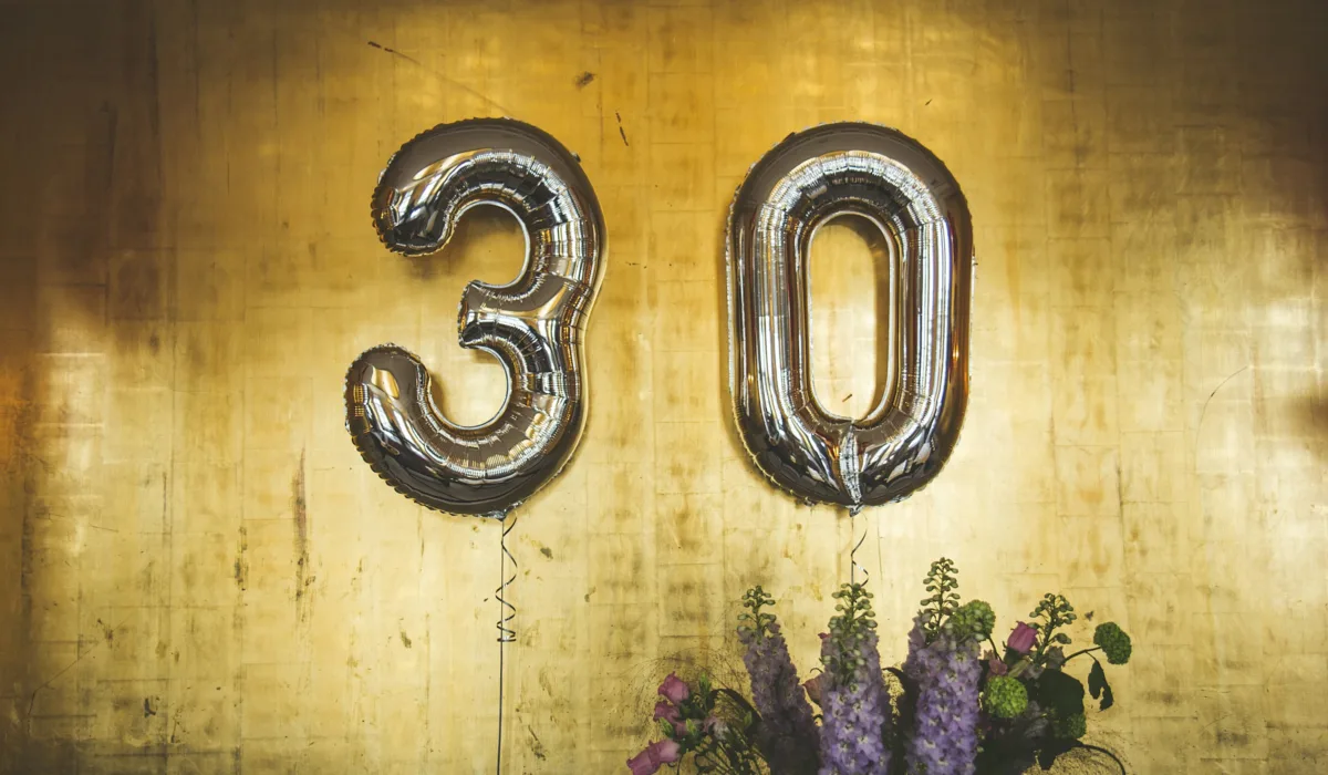 Balloons spelling 30 against a gold wall