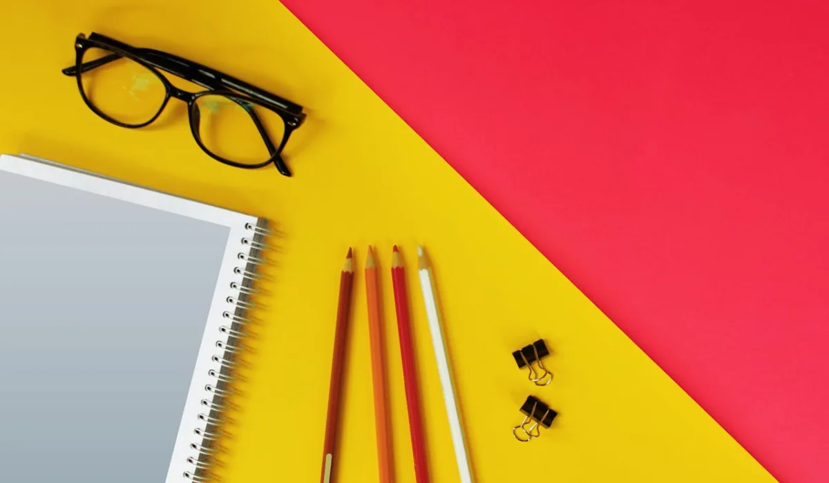 Editorial tools arranged with intention—glasses, notebook, pencils, binder clips—the rule, the tool, the discipline of using both.