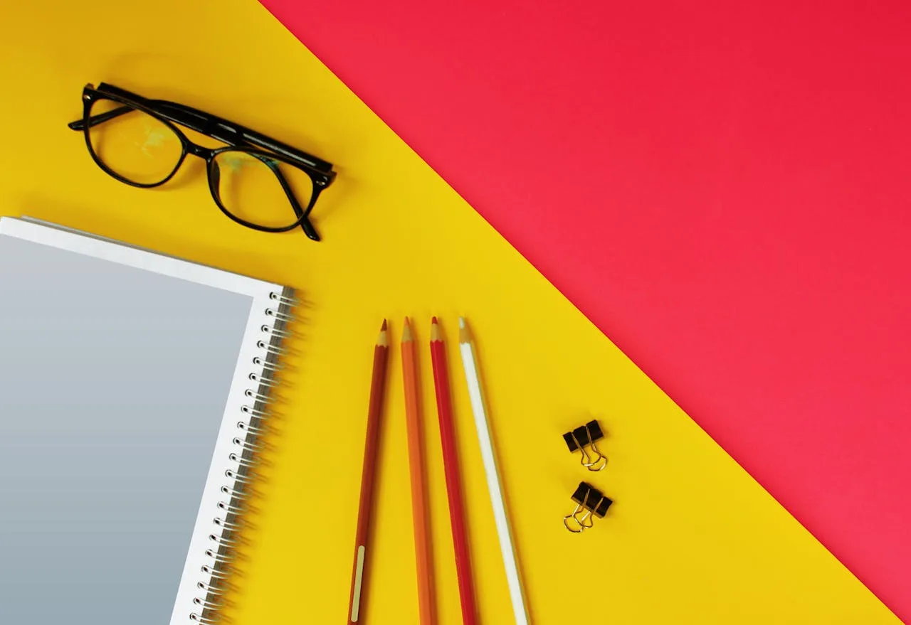 Editorial tools arranged with intention—glasses, notebook, pencils, binder clips—the rule, the tool, the discipline of using both.