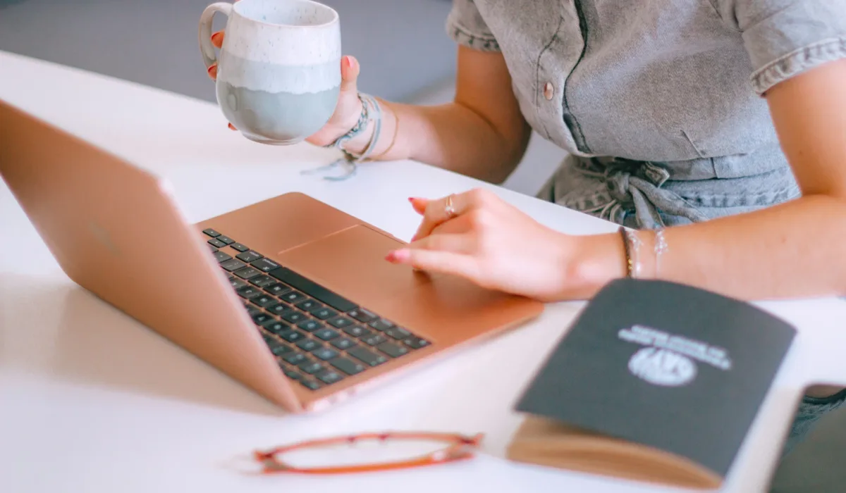 A marketing leader pauses at her laptop with coffee in hand—the moment the dashboard becomes a decision.