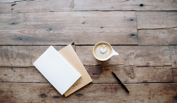 A notebook, cup of coffee and a table on a rustic table
