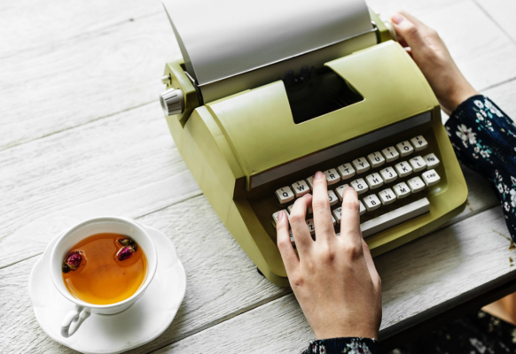 A green typewriter next to a cup of herbal tea